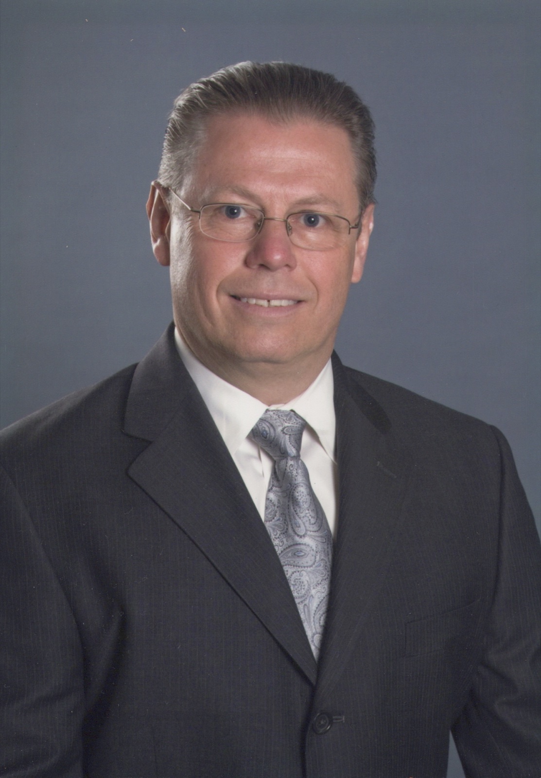 Allen in a suit and tie, his professional portrait