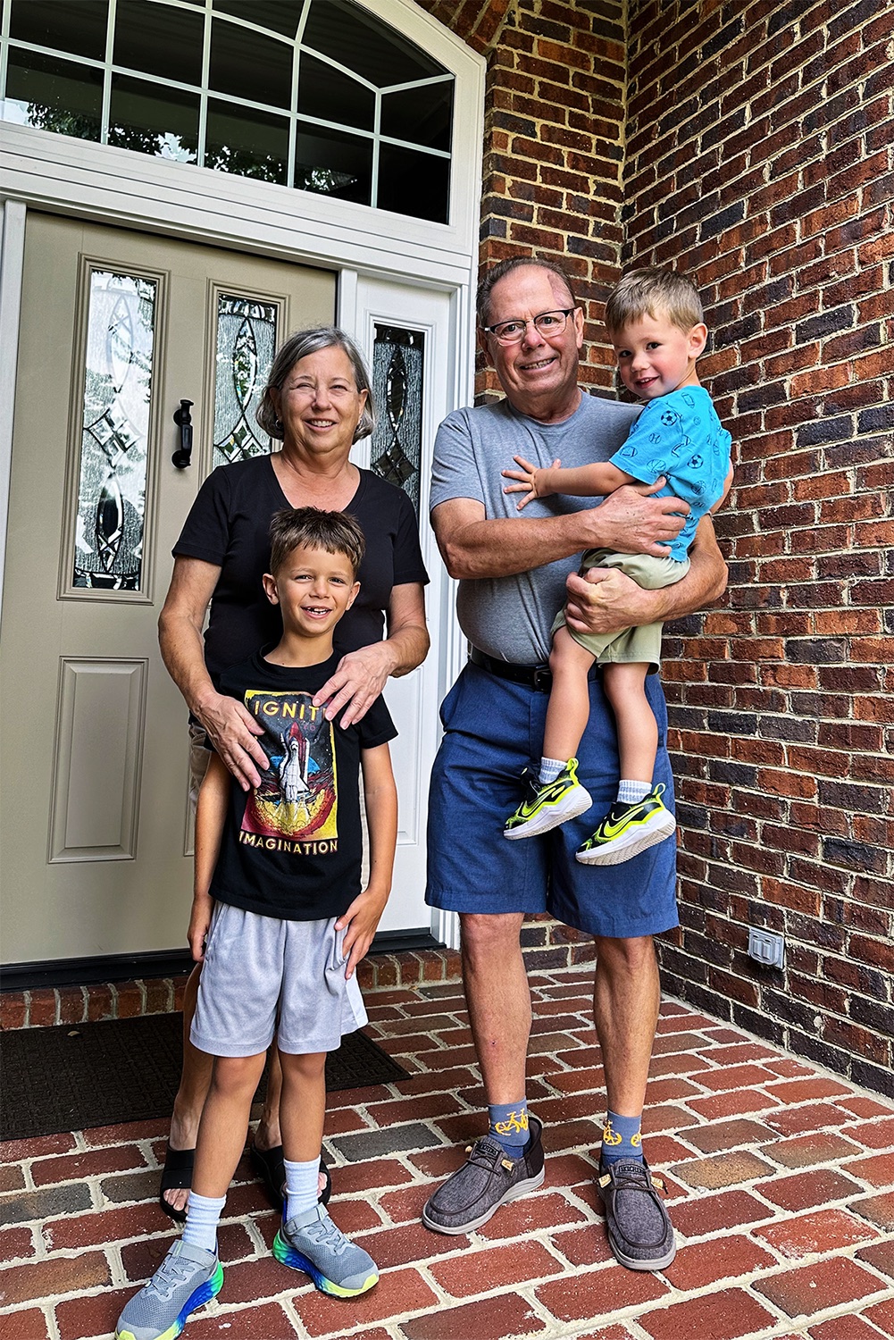 Allen and Clare with their two grandsons on the front porch